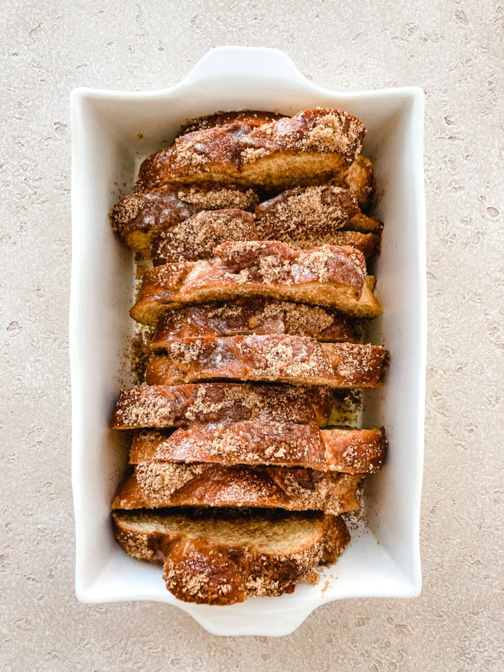 Challah bread topped with cinnamon sugar in a baking dish.