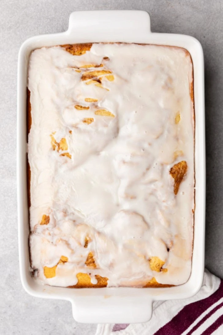 Glazed honey bun cake in a white baking dish.