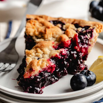 Lemon blueberry crumb pie slice with blueberries and lemon.