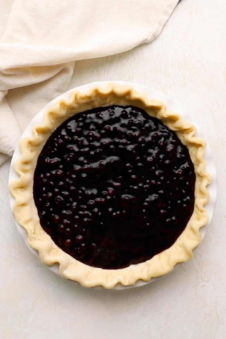Blueberry filling added to a pie crust.