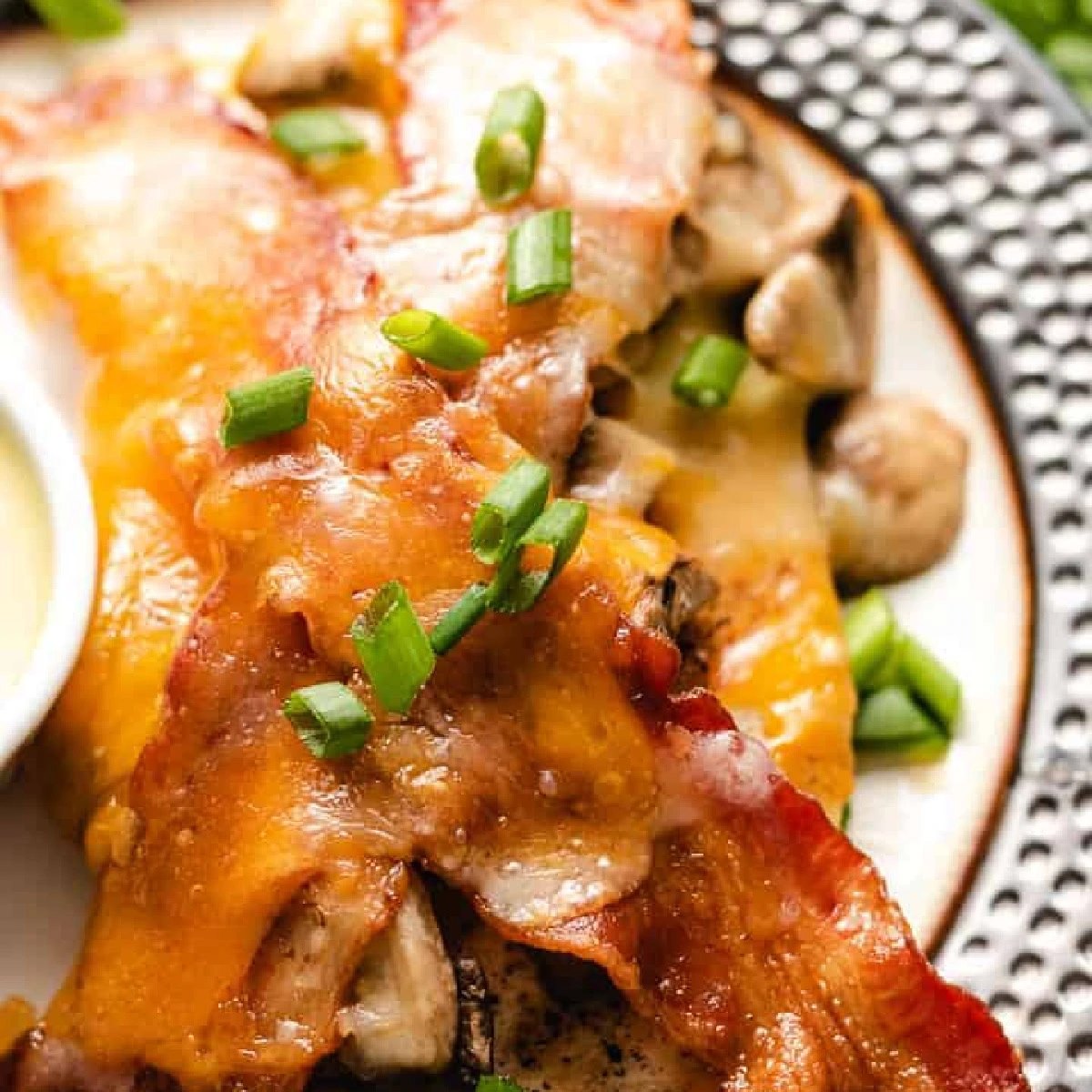 Loaded chicken breast with bacon and cheese on a plate.