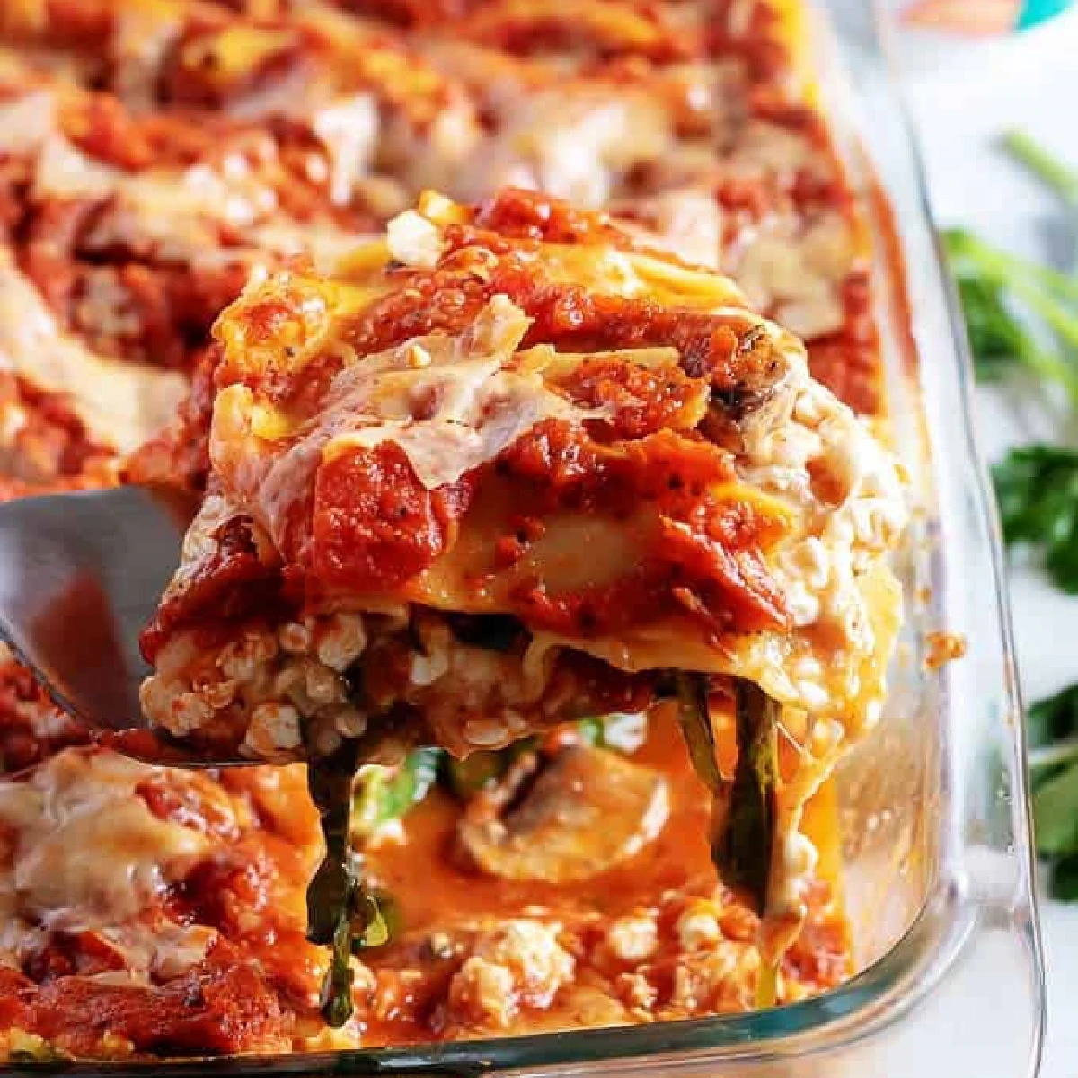 Slice of mushroom lasagna being held up from the pan.