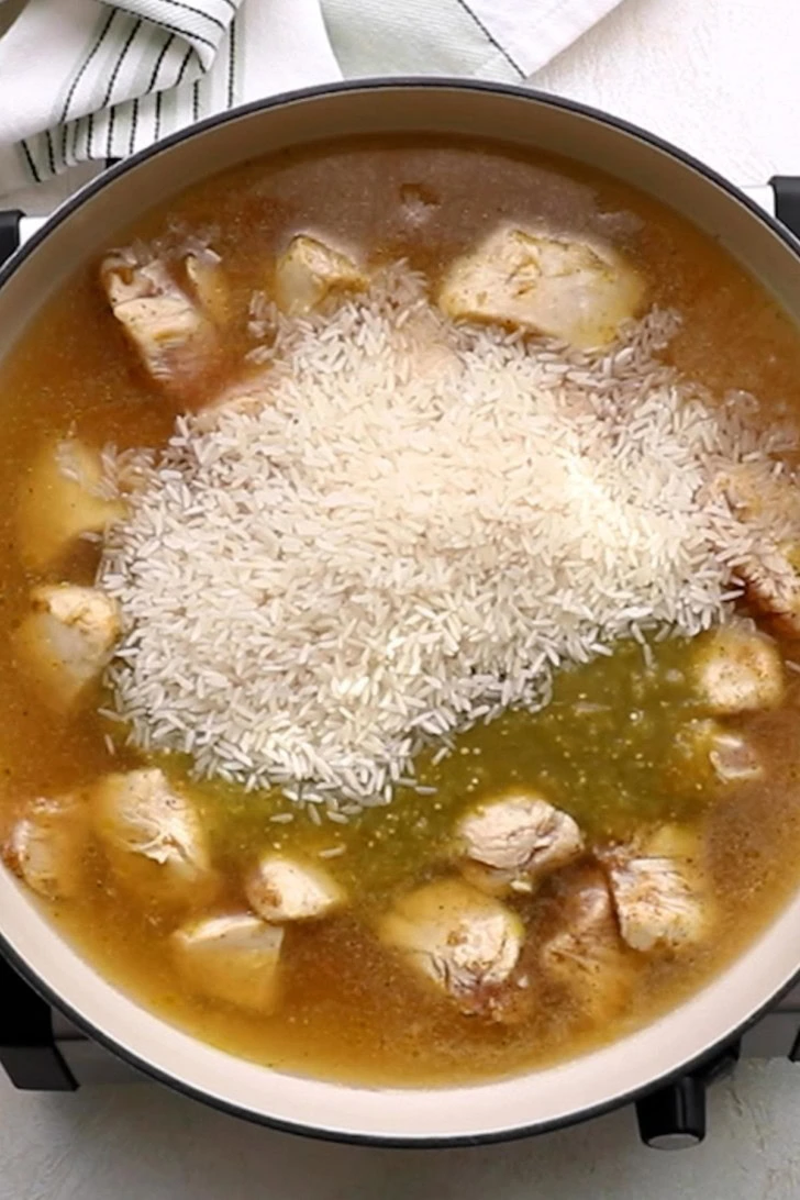 Rice added to salsa verde chicken and rice skillet before cooking.