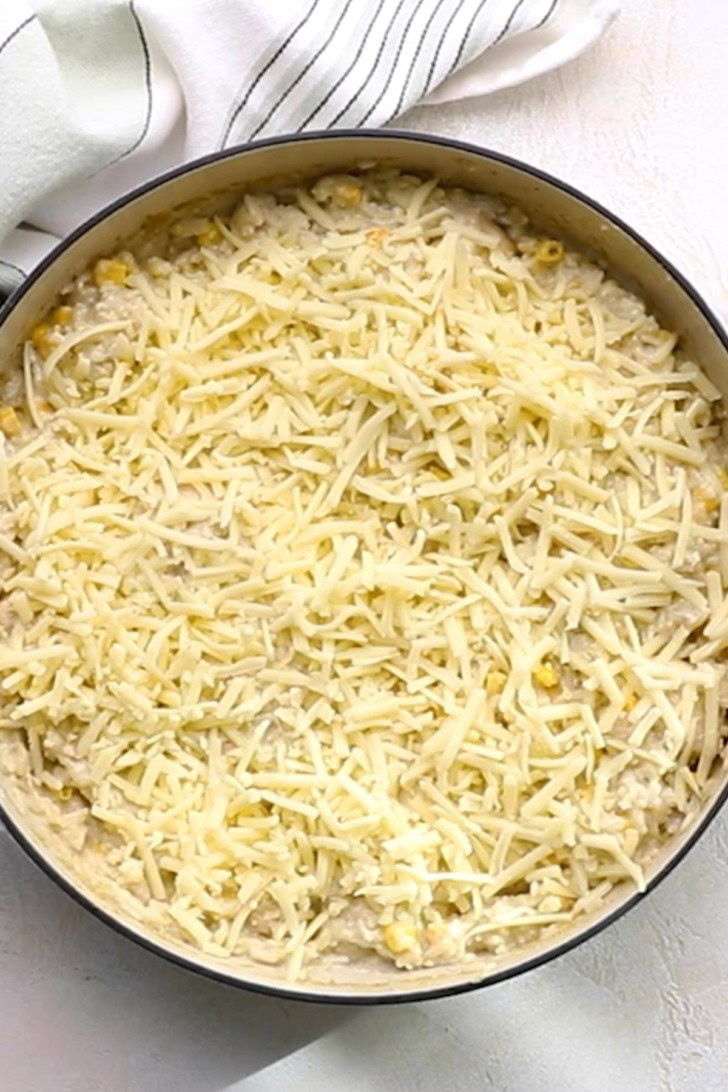 Shredded cheese added to salsa verde chicken and rice skillet.