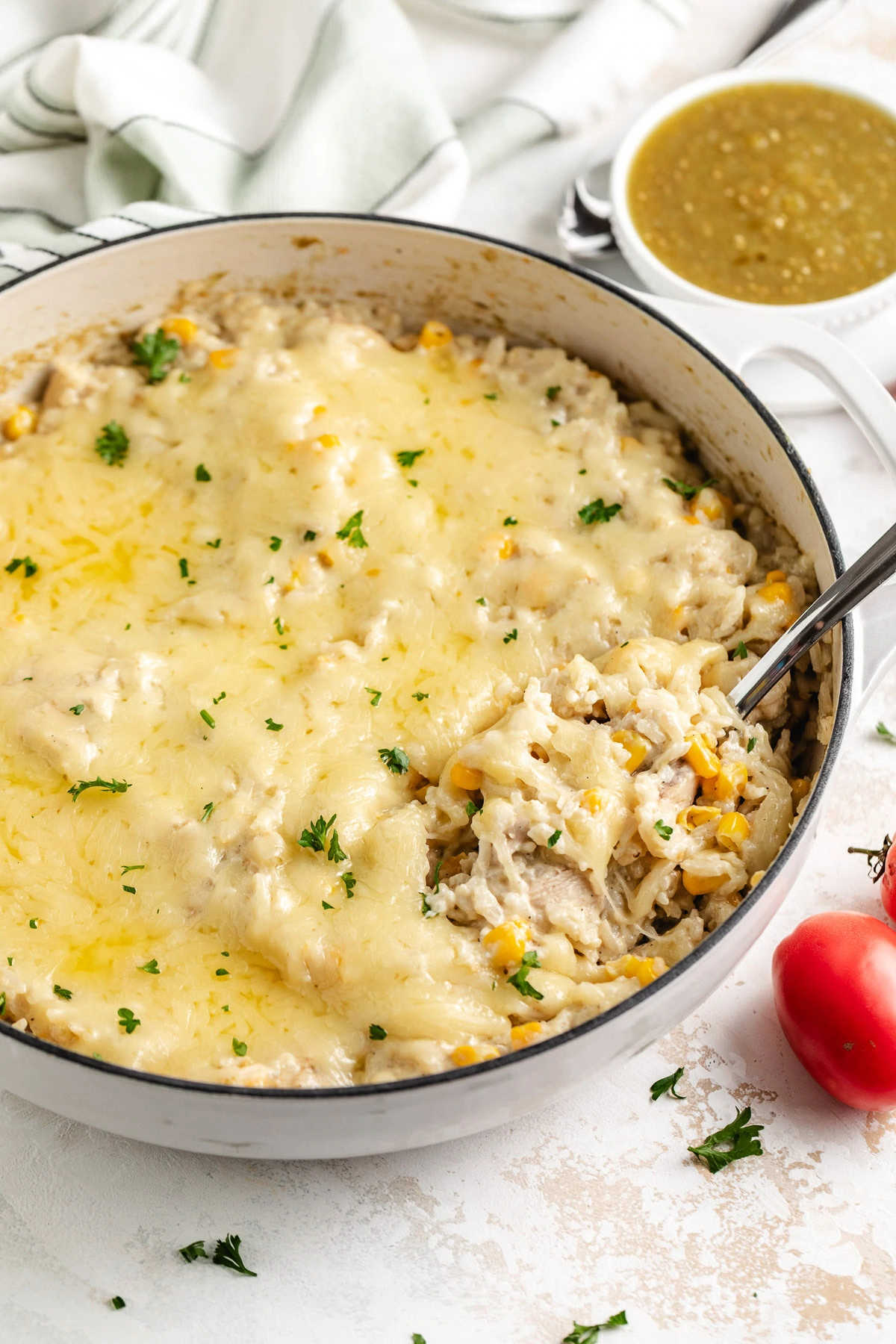 Cheesy chicken and rice skillet with corn, parsley, and salsa verde.