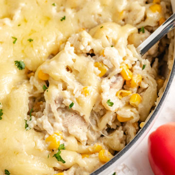 Close-up of salsa verde chicken and rice skillet with melted cheese and corn.