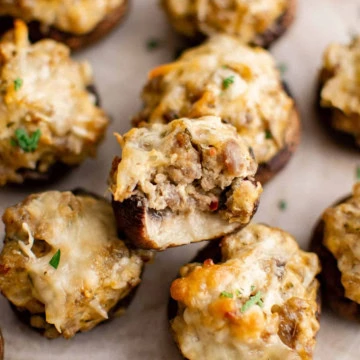 Cheesy sausage stuffed mushrooms on a sheet pan.