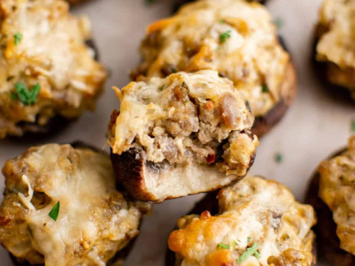 Cheesy sausage stuffed mushrooms on a sheet pan.