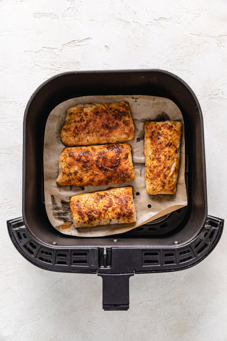 Cooked mahi mahi fillets in an air fryer basket.