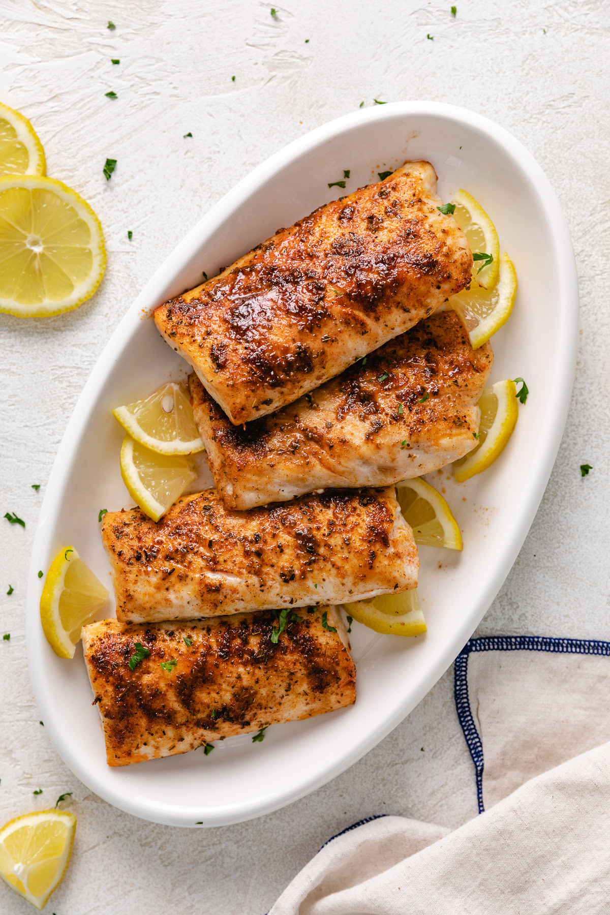 Air fryer mahi mahi on a white platter with lemon wedges.