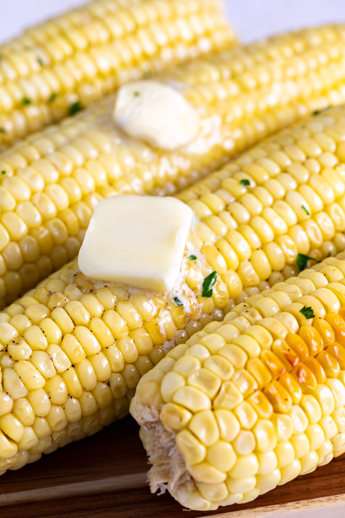 Buttered baked corn on the cob with chopped parsley.