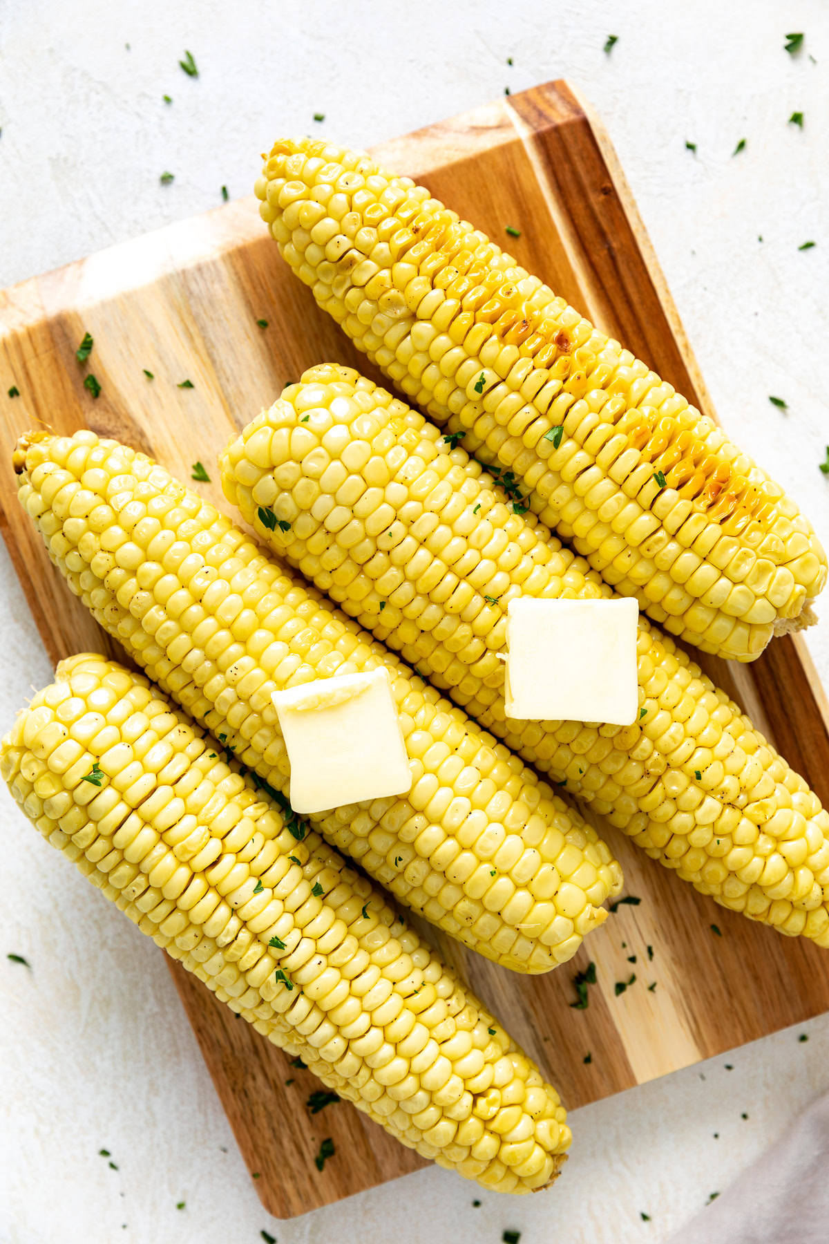 Baked corn on the cob topped with pats of butter.