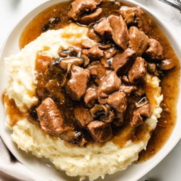 Overhead view of beef tips and gravy served over mashed potatoes.