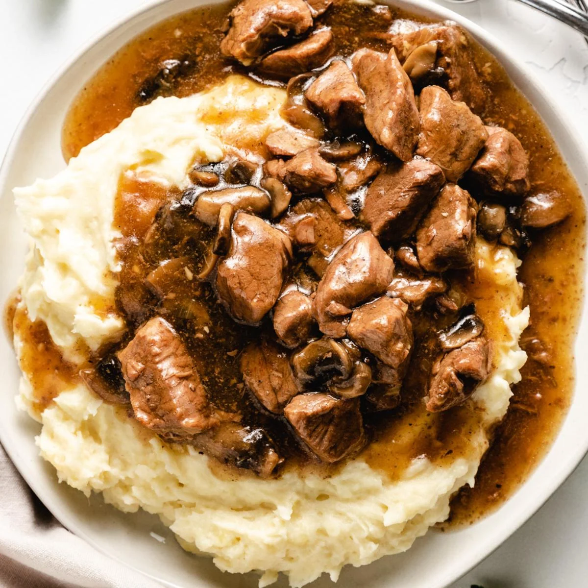 Overhead view of beef tips and gravy served over mashed potatoes.