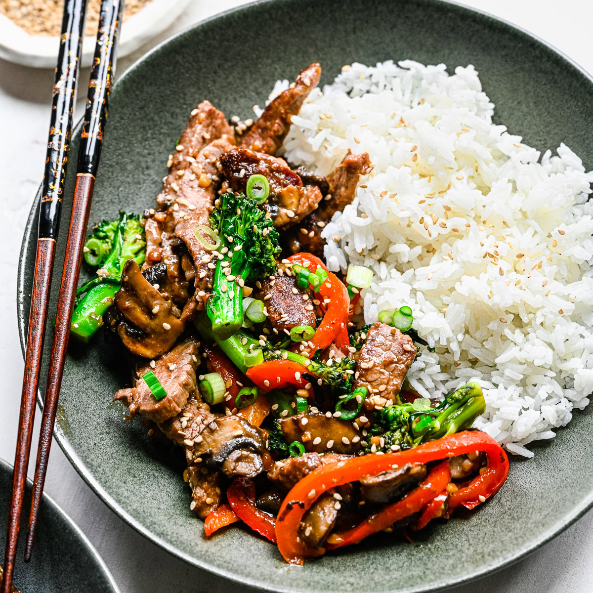 Steak strips with broccoli, mushrooms, red bell peppers, and white rice in a bowl.