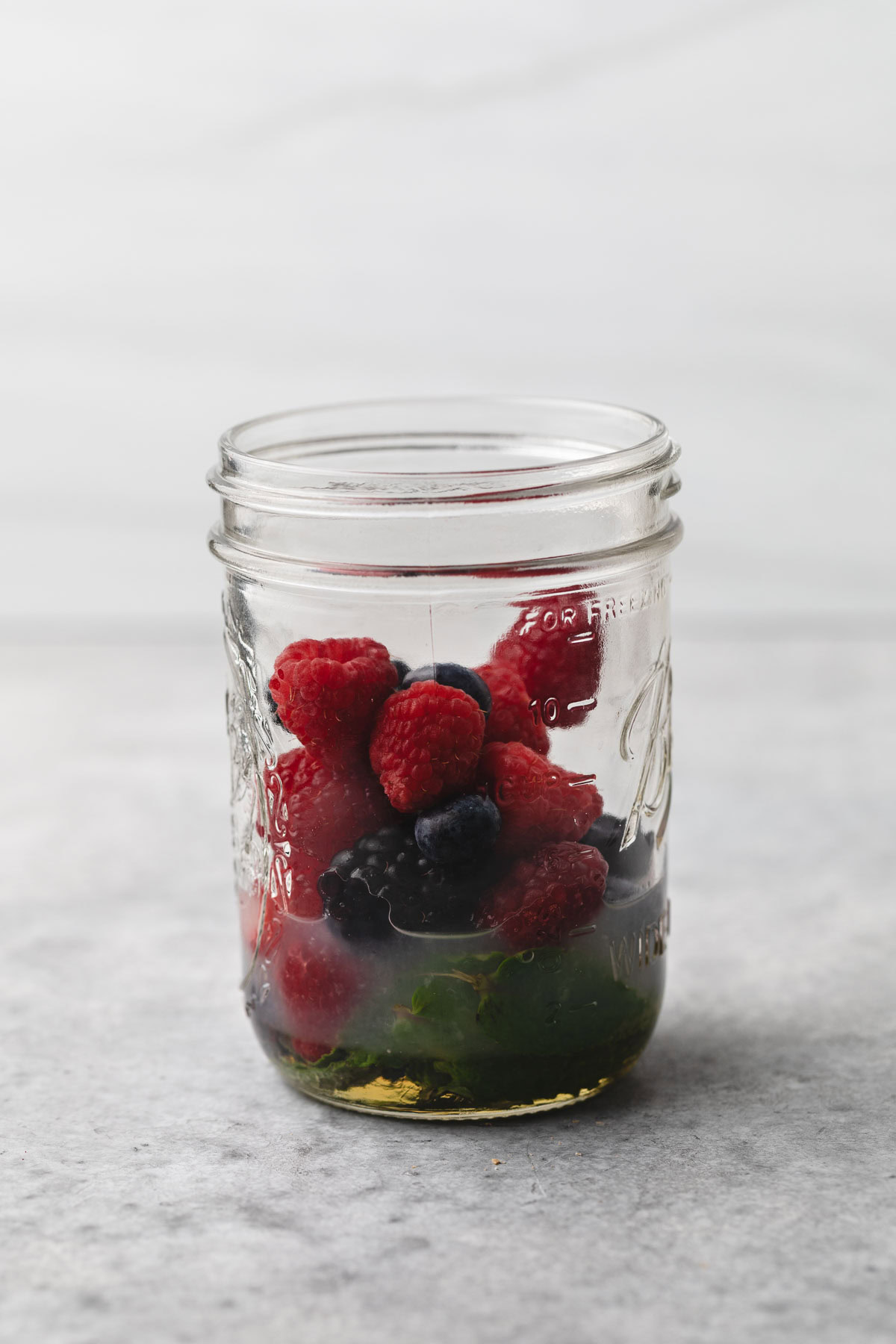 Ingredients for a berry mocktail in a mason jar.