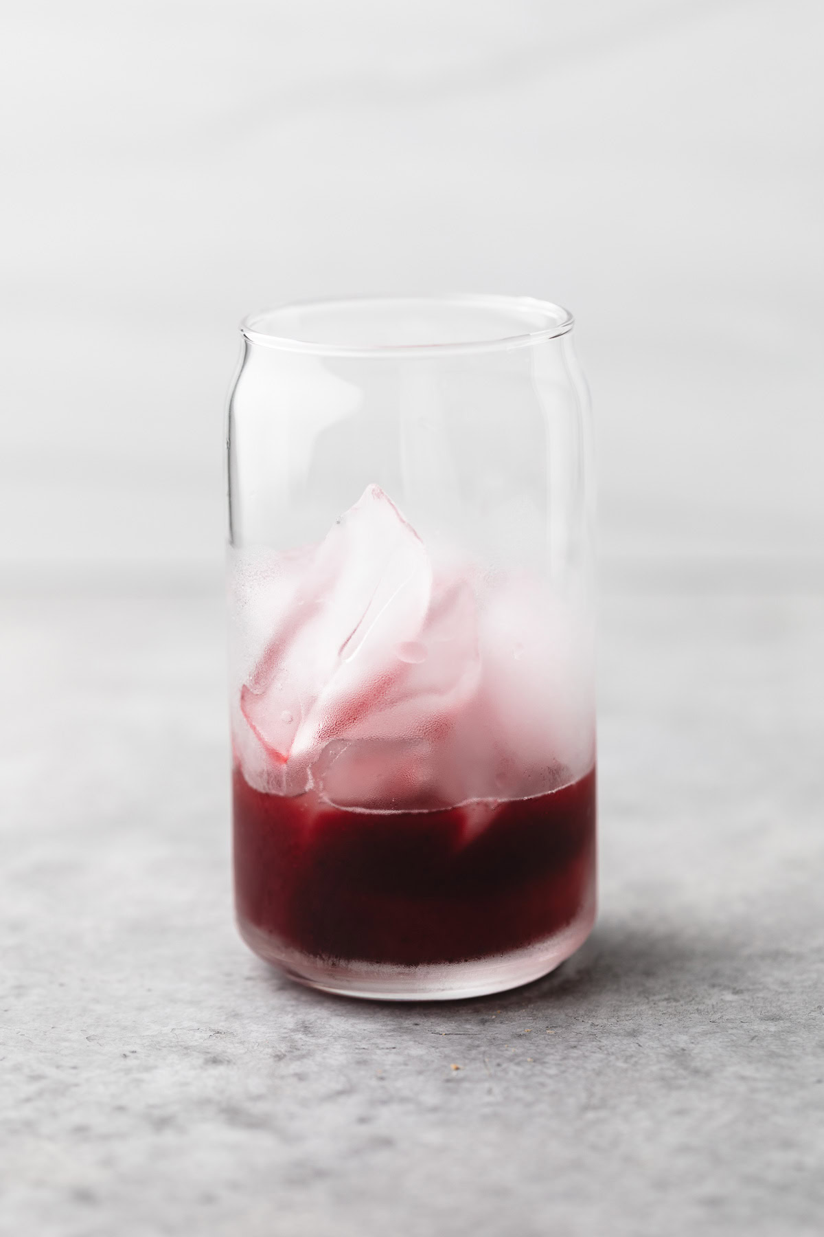 Mixed berry syrup poured in a class over ice.