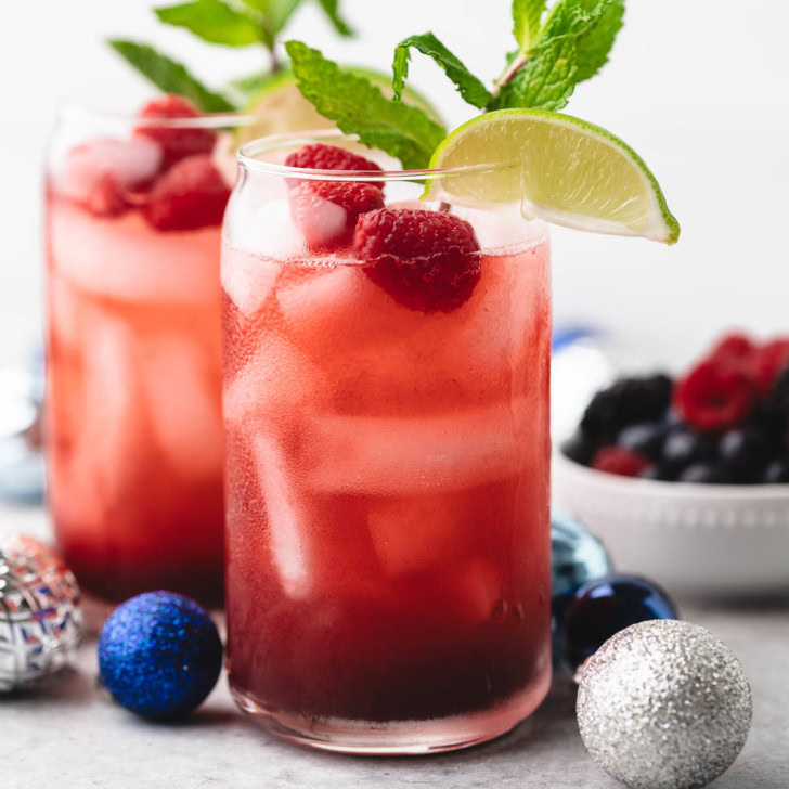 Mixed berry mocktail surrounded by christmas ornaments.