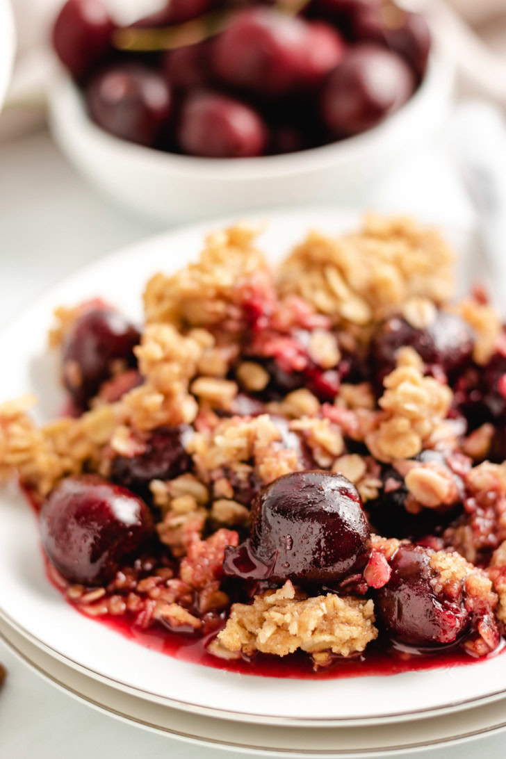 Oat topped cherry crisp on a stack of plates.