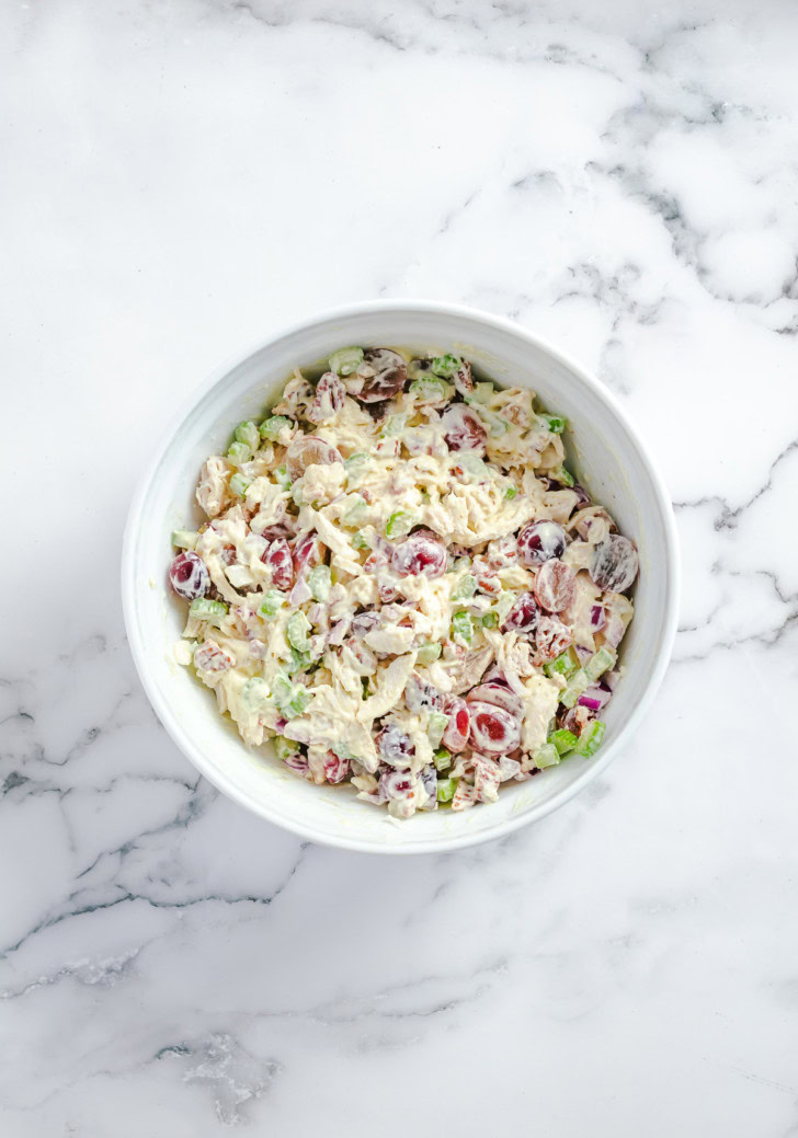 Chicken salad ingredients folded together with creamy dressing.