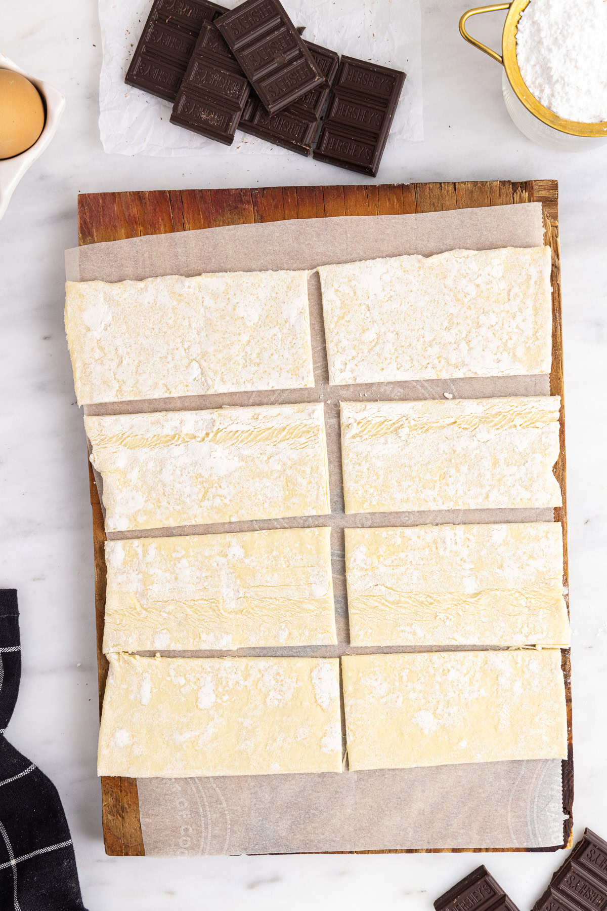 Puff pastry sheets cut into rectangles with chocolate bars nearby.
