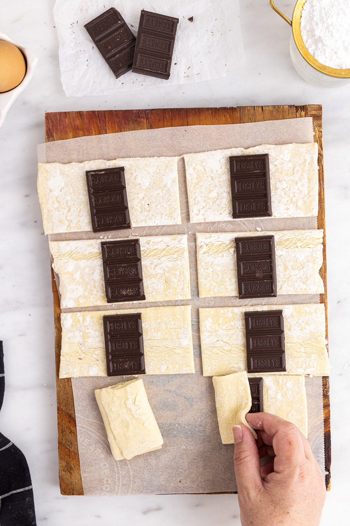 Chocolate bar pieces placed on puff pastry rectangles as the dough is folded over the filling.