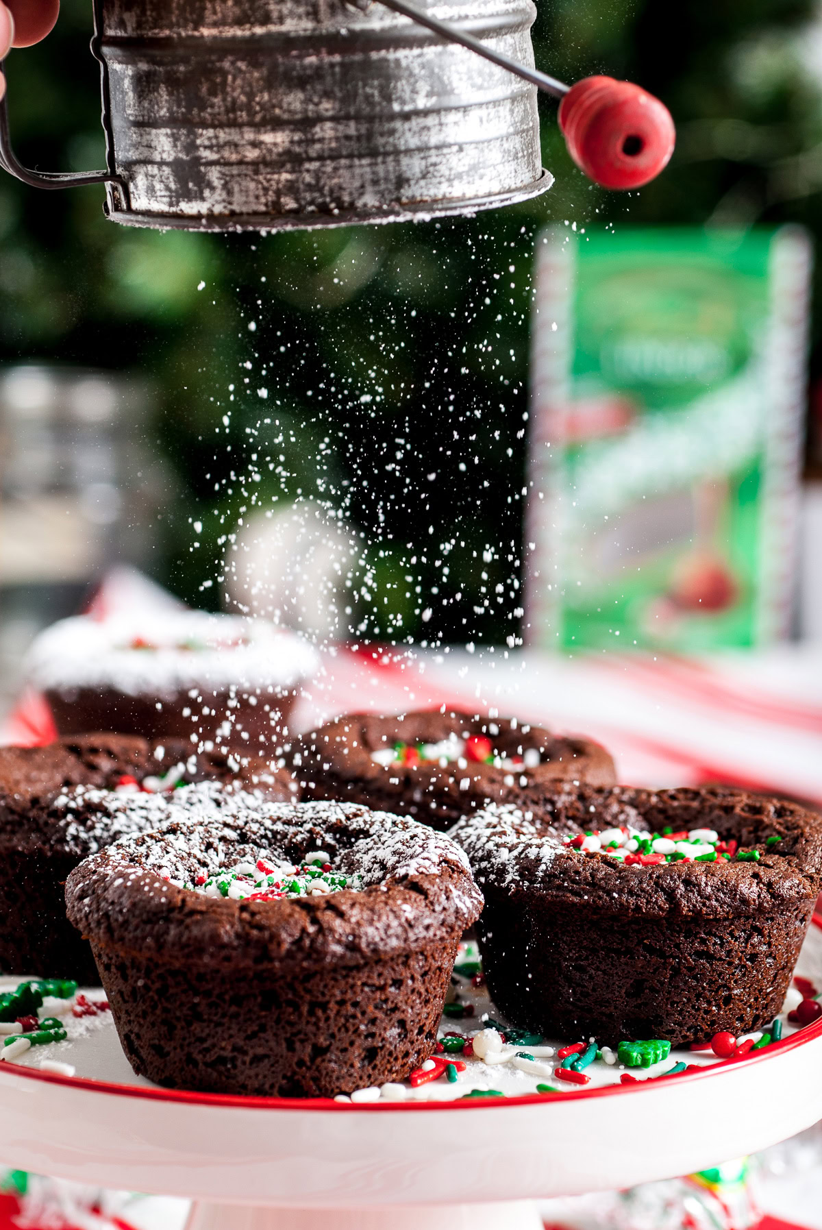 Powdered sugar being sifted over Christmas brownies on a serving tray.