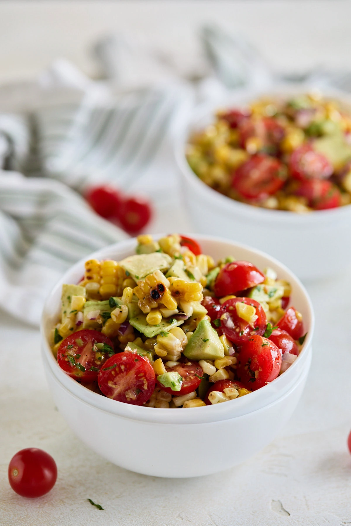 White bowl filled with corn tomato and avocado salad.