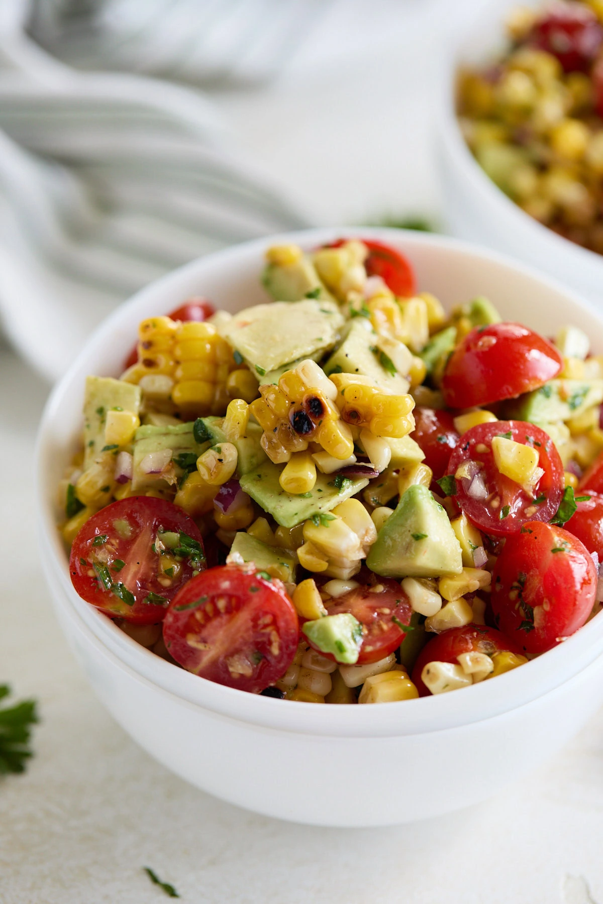 Close up view of tomato corn and avocado salad in a bowl.