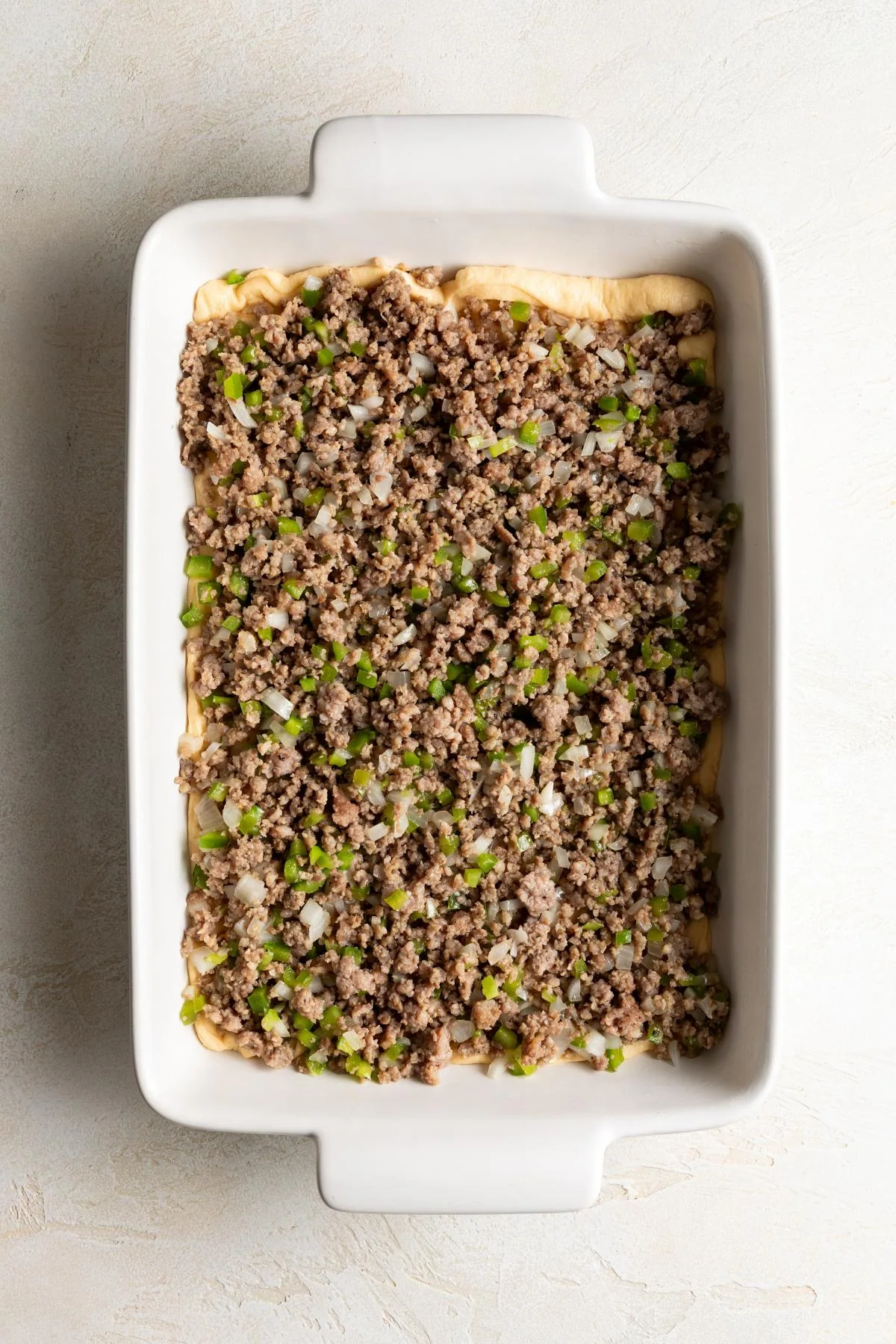 The sausage mixture is spread over the crescent dough.