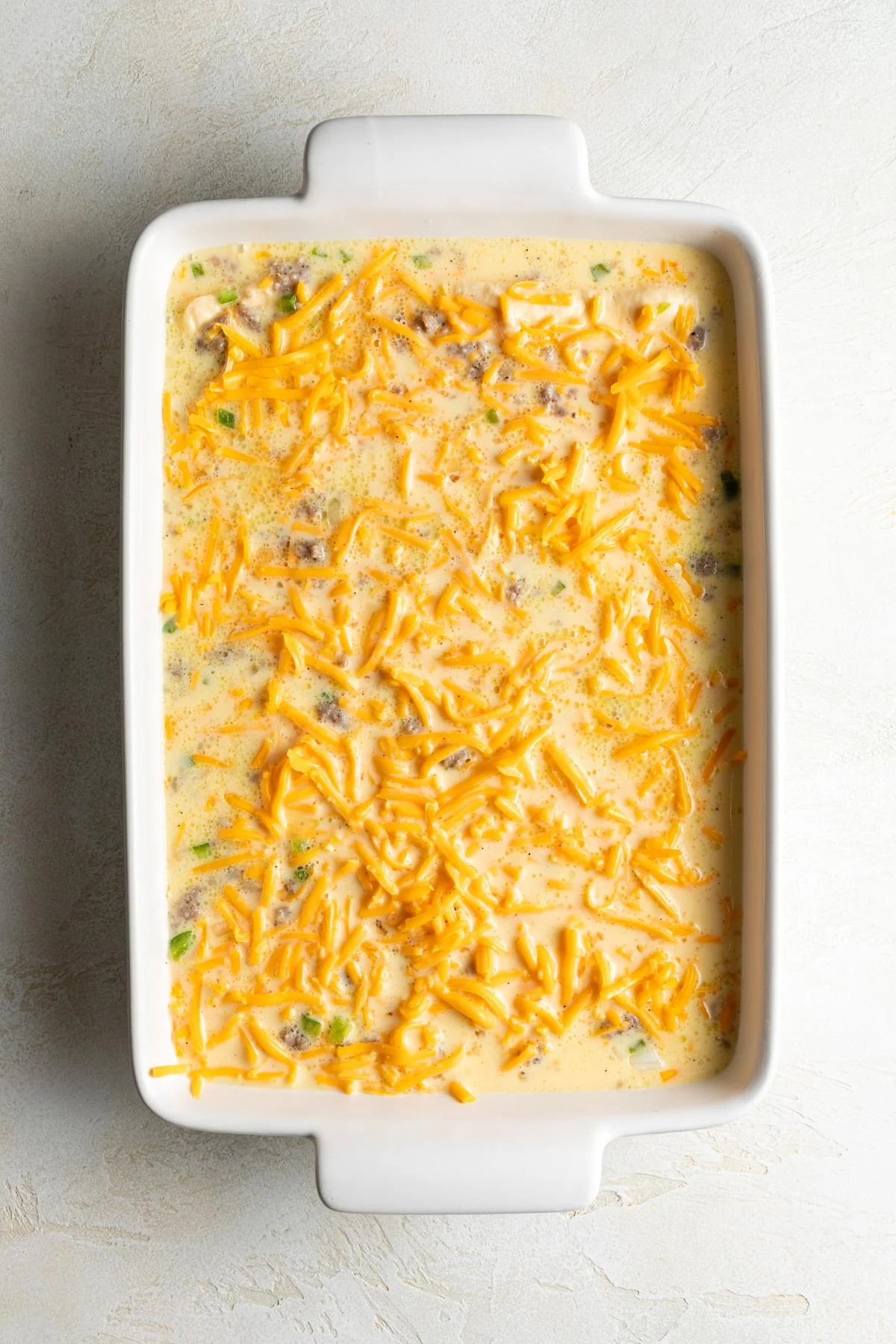 The egg mixture is poured over the sausage and cheese.