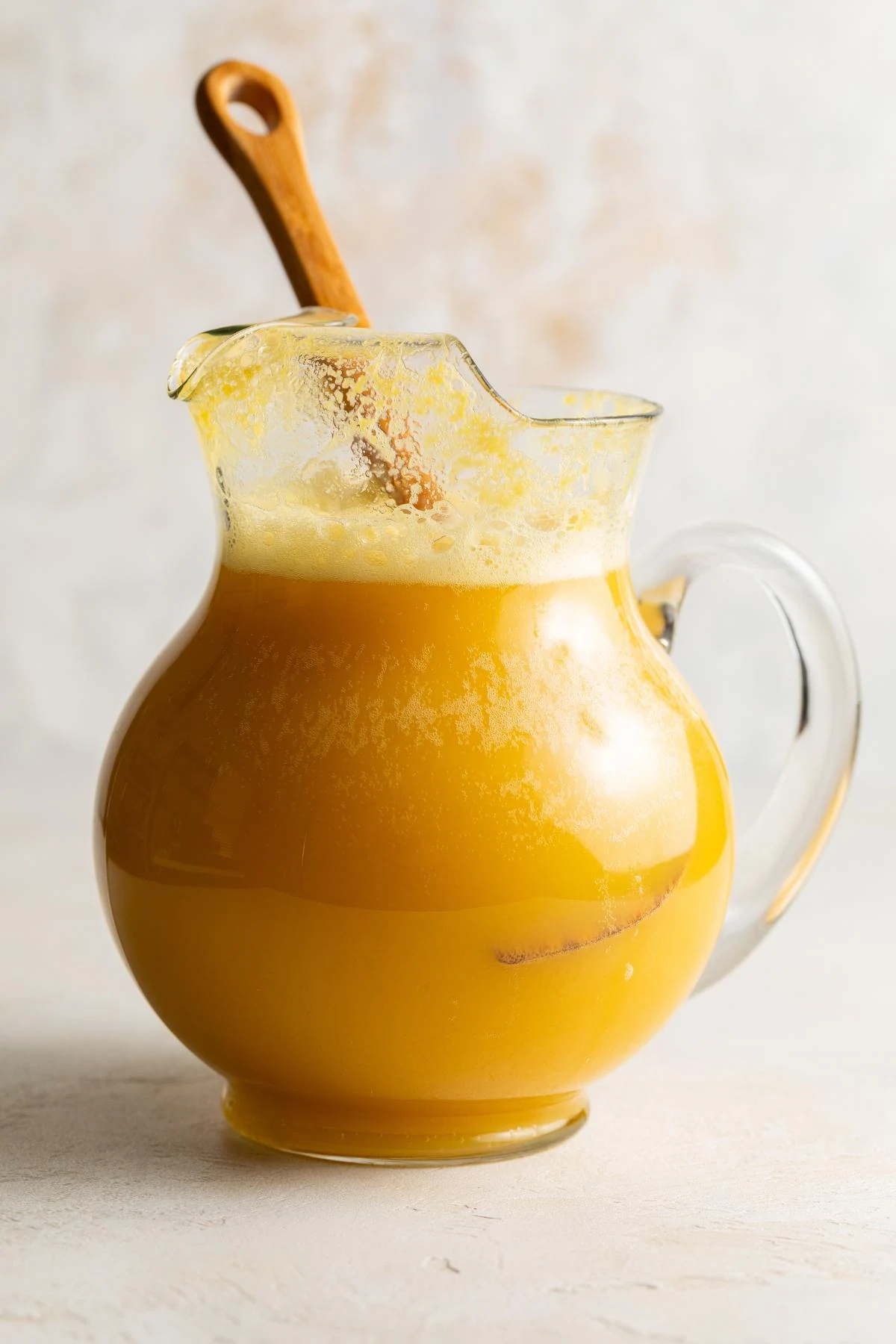 Stirring orange juice concentrate and ginger ale together in a pitcher.