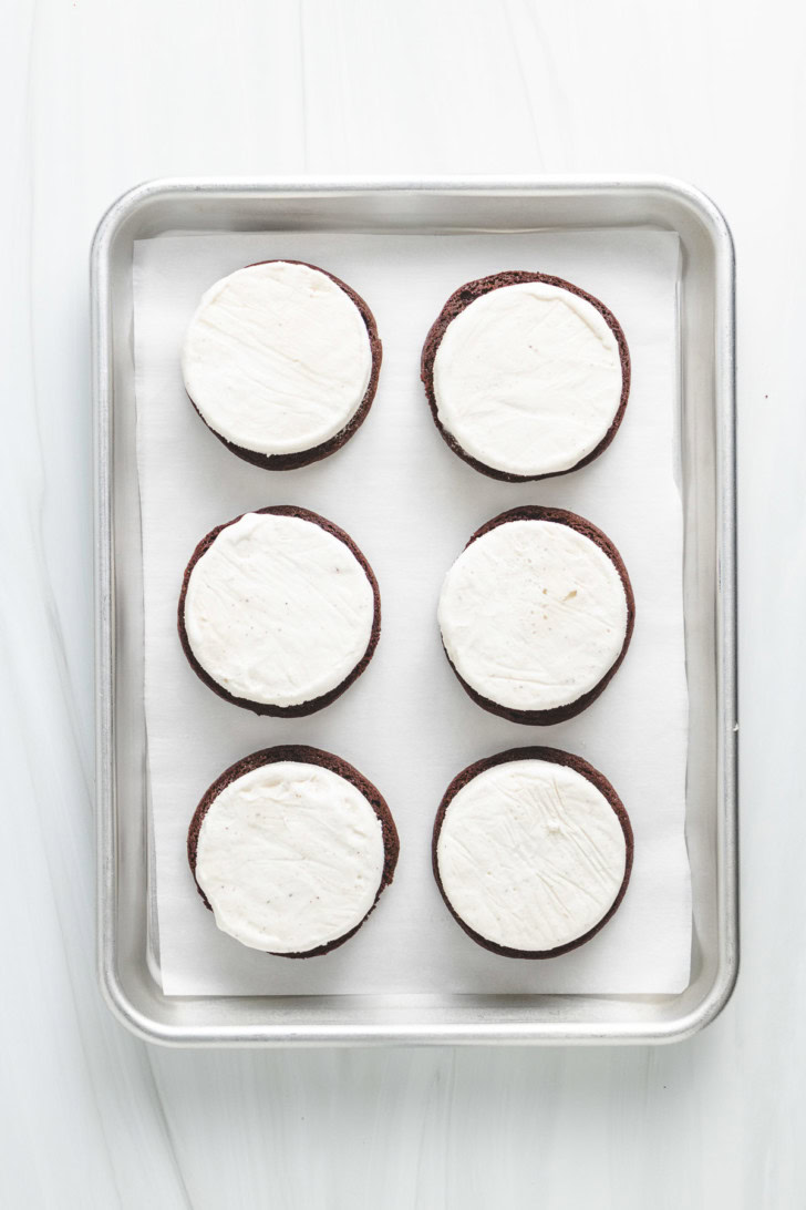 Chocolate cookies topped with round vanilla ice cream pieces.
