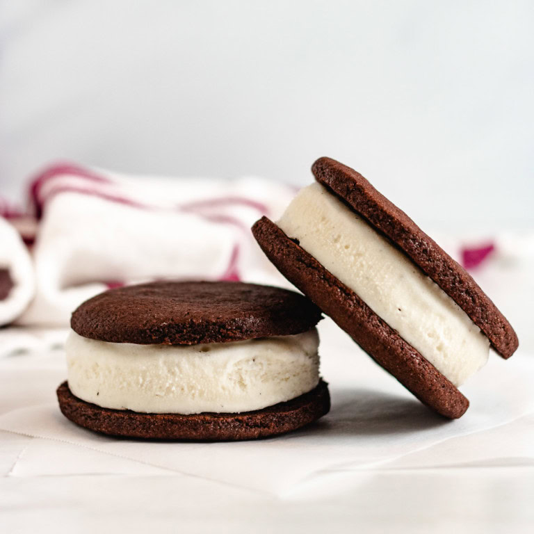 Two homemade ice cream sandwiches stacked on parchment paper.