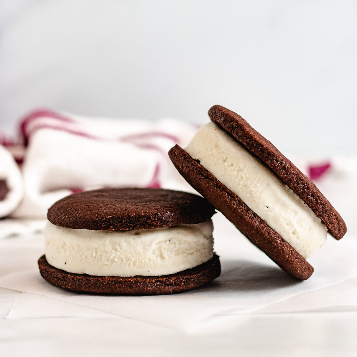 Two homemade ice cream sandwiches stacked on parchment paper.