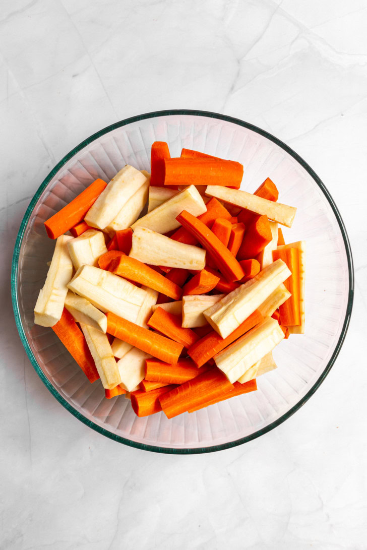 Cut carrots and parsnips in a glass mixing bowl.