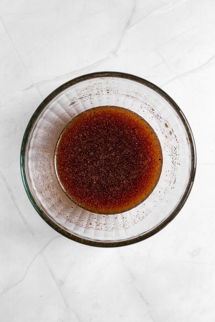 Honey and spices mixed in a glass measuring cup.