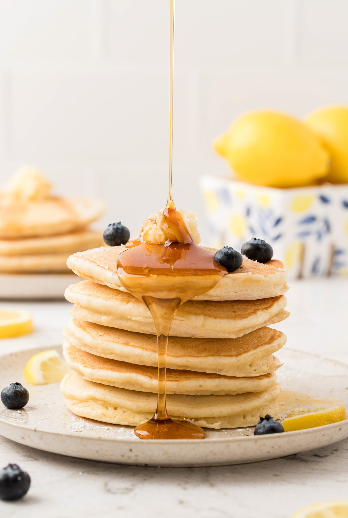 Syrup drizzled over lemon ricotta pancakes with blueberries.