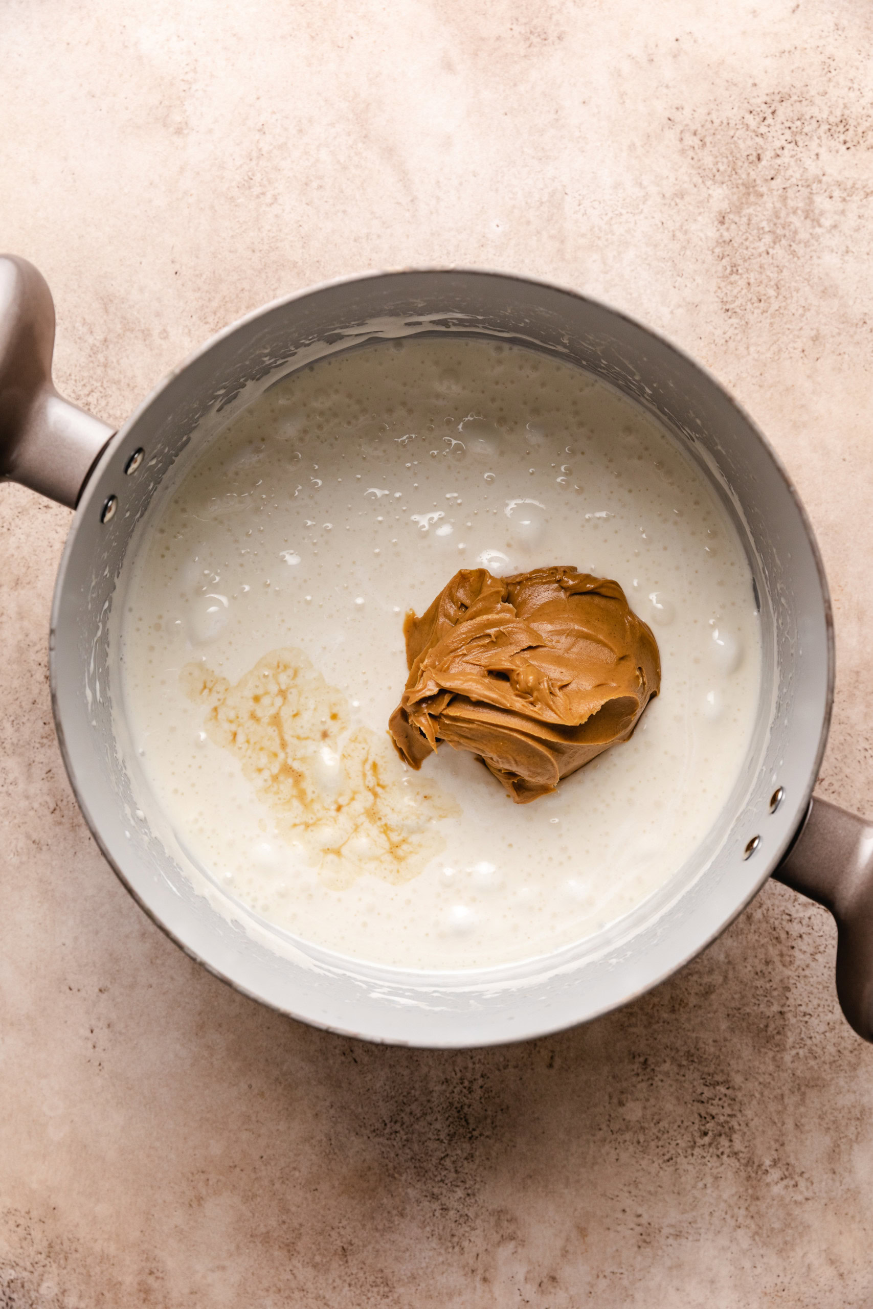 Peanut butter added to melted marshmallows in a saucepan.