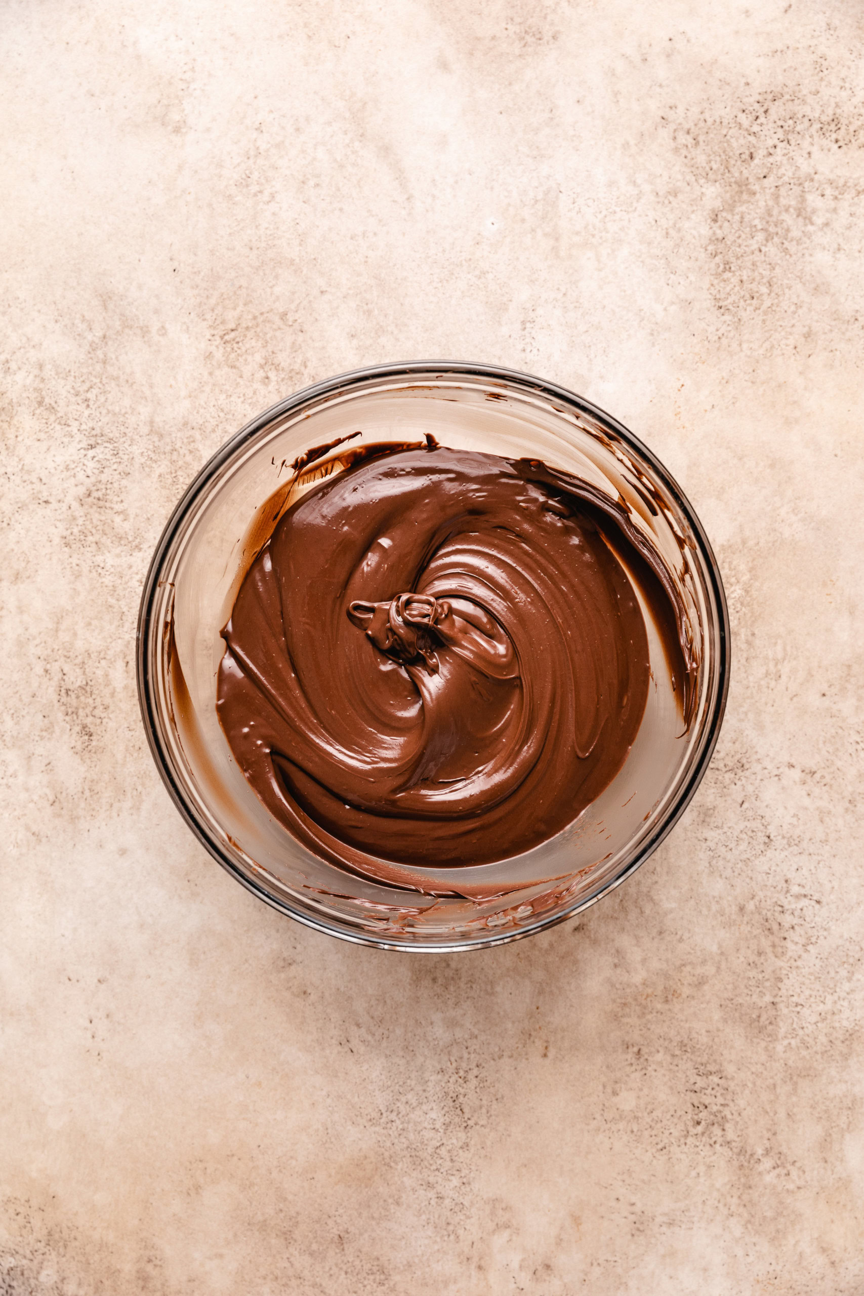 Melted chocolate stirred in a glass bowl.