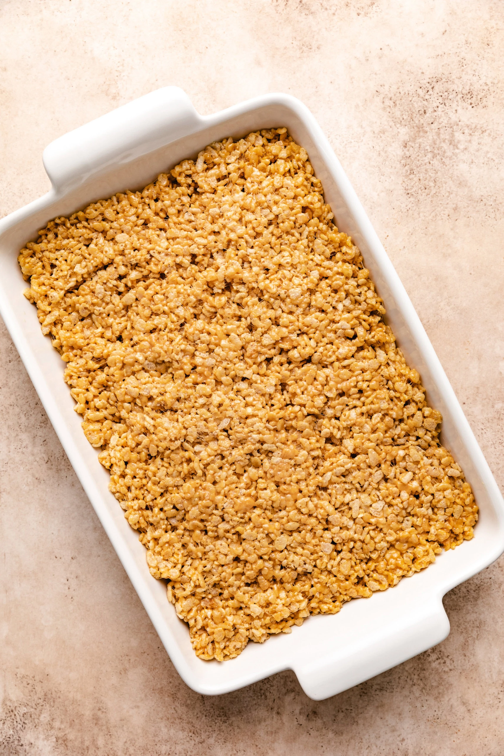 Rice krispie mixture pressed into a white baking dish.