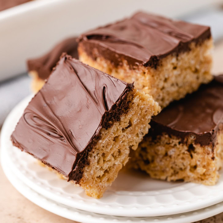 Peanut butter rice krispie treats topped with chocolate on a white plate.