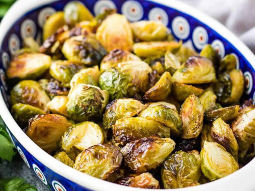 Close-up of roasted Brussels sprouts in a serving bowl.