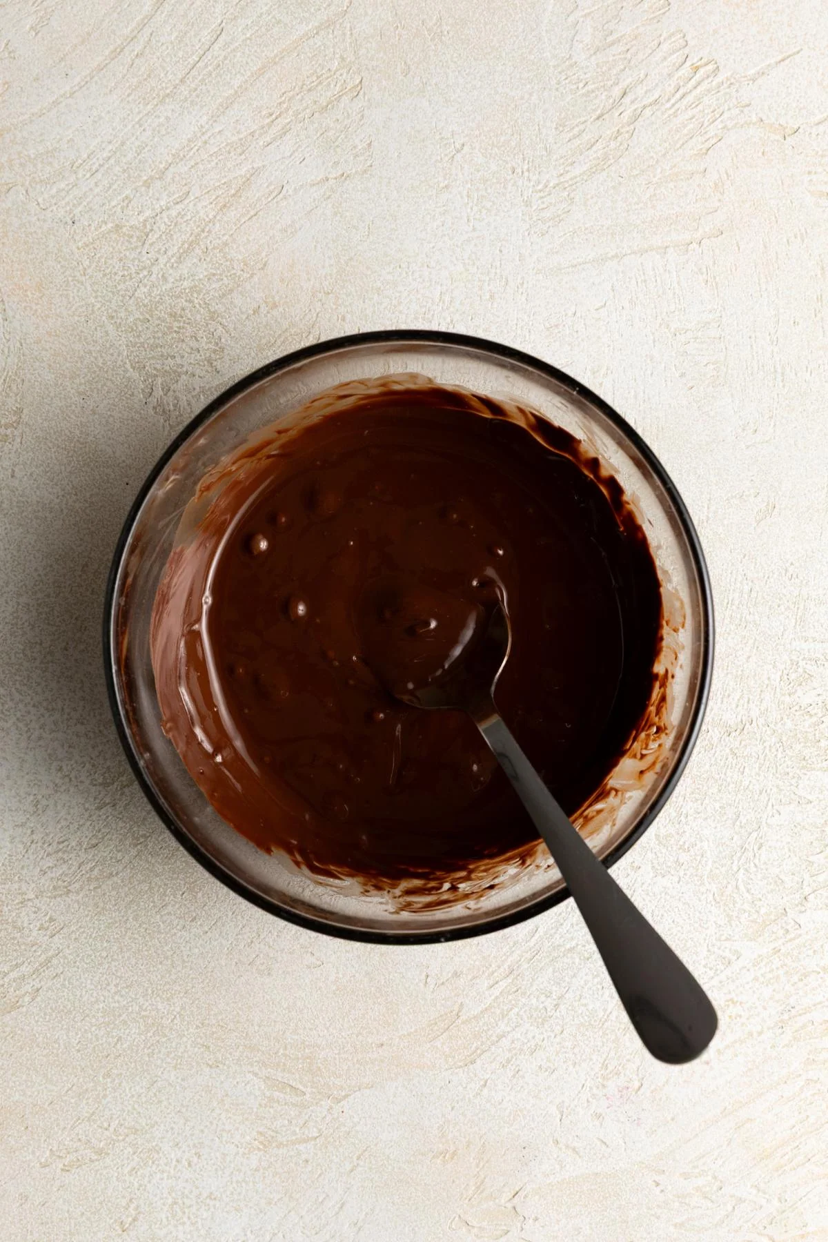 Melted chocolate in a glass bowl with a spoon.
