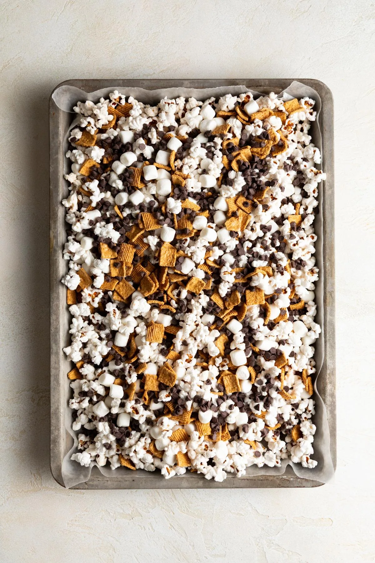S'mores popcorn mix spread across a parchment-lined sheet pan.