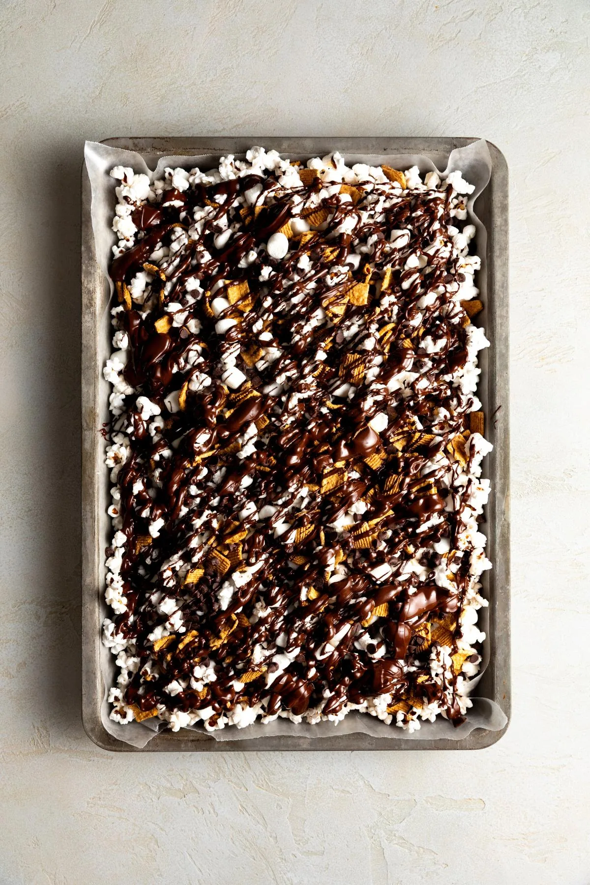 Close-up of chocolate-drizzled popcorn with marshmallows and cereal.