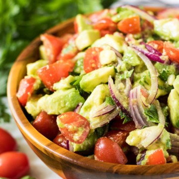 Close up view of tomato avocado salad in a wooden bowl.