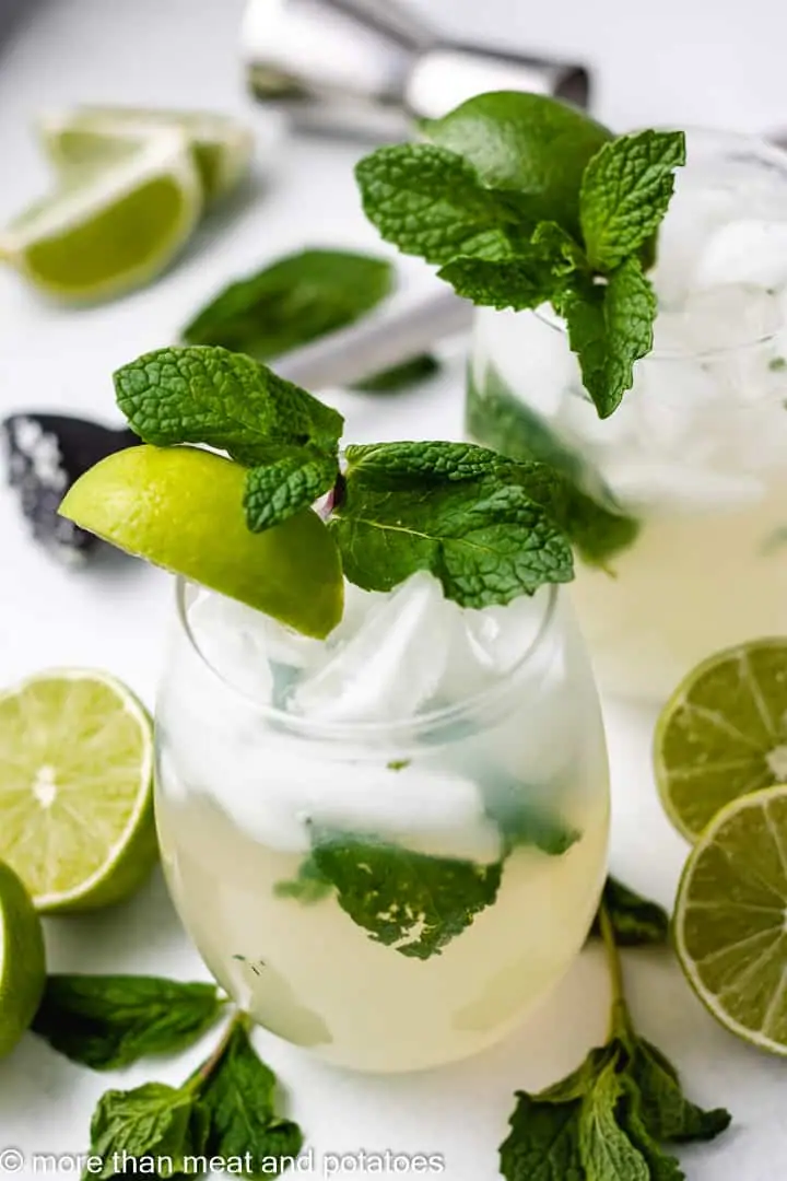 Mint and lime mocktails served over ice with fresh limes around the glasses.