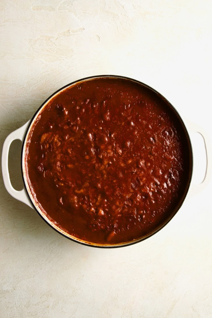 Saucy beans simmering in a white pot.