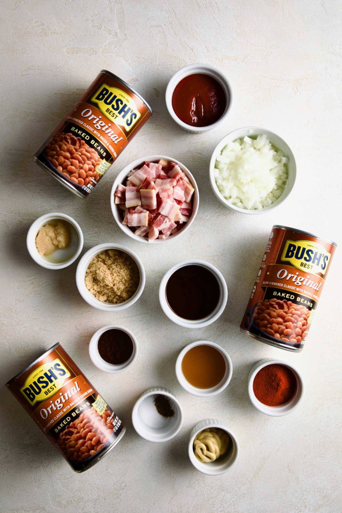 Ingredients for baked beans arranged on a light surface.